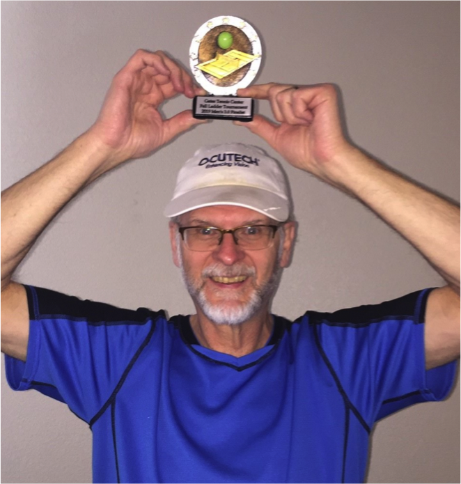 Low Vision Specialist wearing Ocutech hat and holding tennis trophy above head