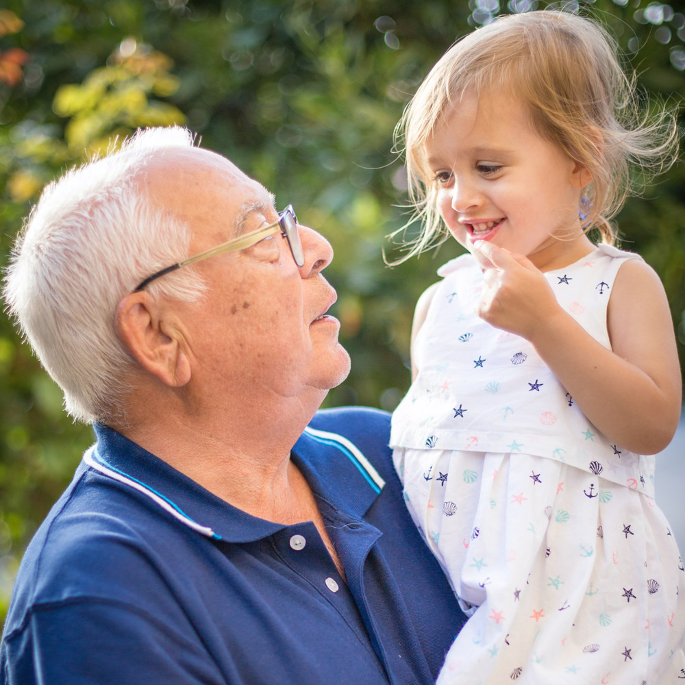 grandfather wearing glasses holding his granddaughter