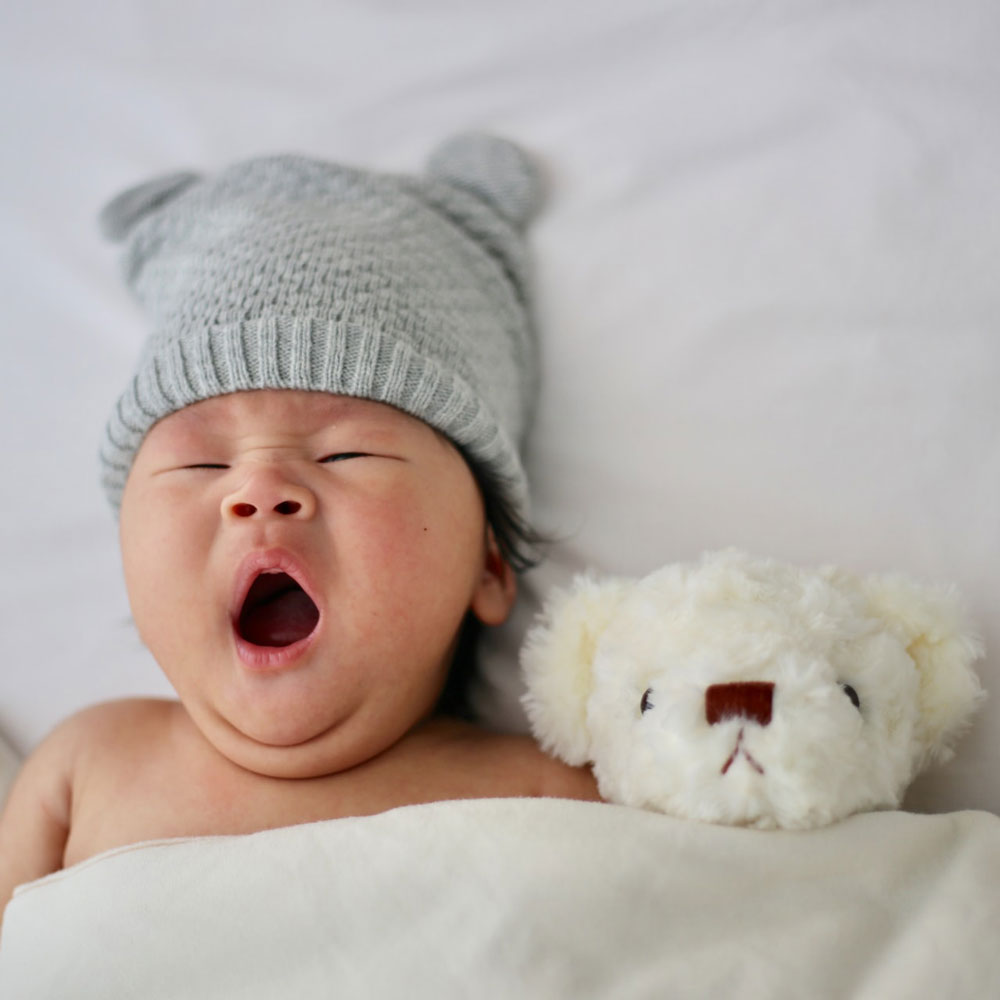 baby wearing a grey hat yawning