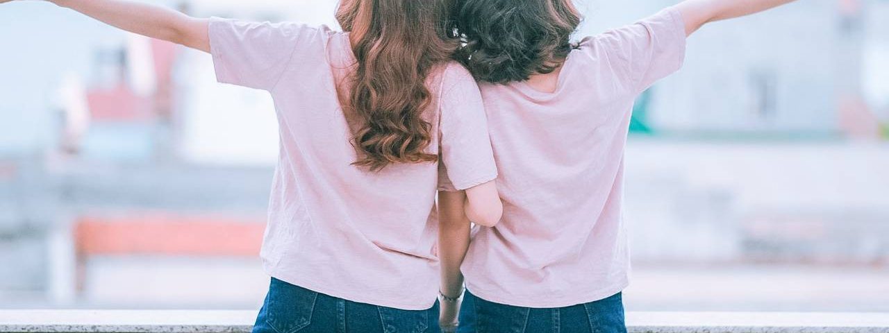 back of two young girls arms spread