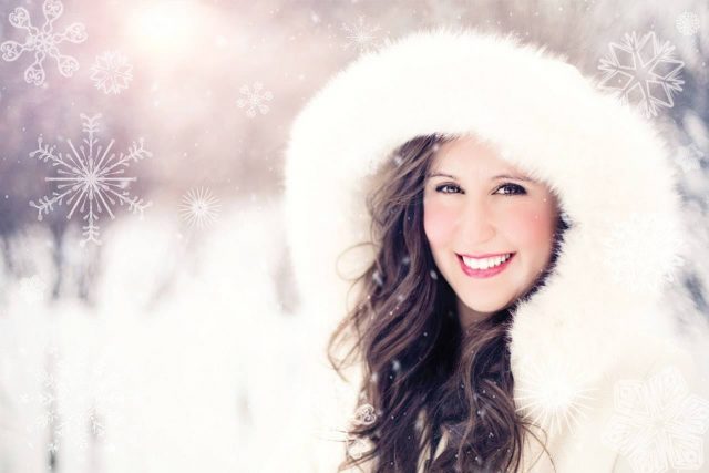 woman wearing white hood in winter smiling showing white teeth