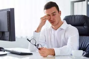 Man suffering from dry eyes in front of computer