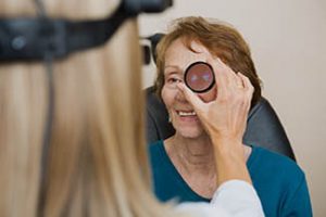 Female optician examining senior womans eye with binocular indi