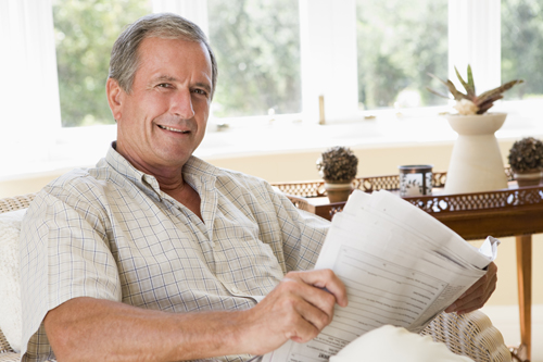 Man in living room reading newspaper smiling olathe ks