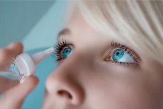 woman applying eyedroppers close up.png