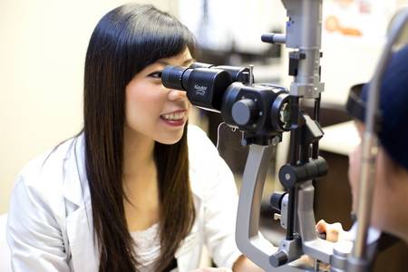 beautiful asian female eye doctor performing an eye exam