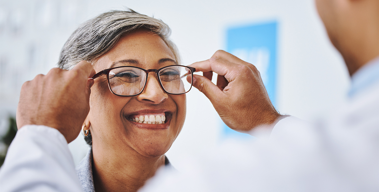 Optometry, smile and woman with prescription glasses, optician and helping client with product.