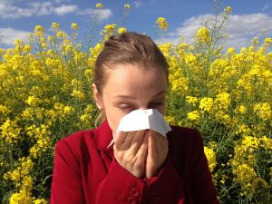 woman sneezing surrounded by flowers, eye allergies - Eye Doctor, Waco, TX