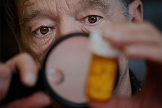 Man Examining Instructions On Medicine Bottle