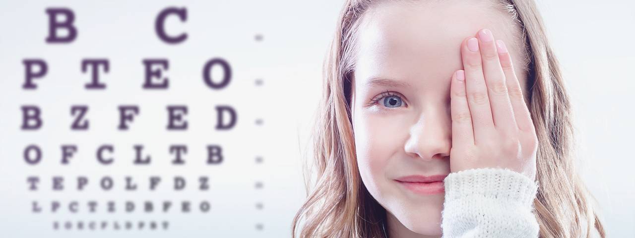 Girl in front of eye chart, eye doctor, Fort Collins, CO