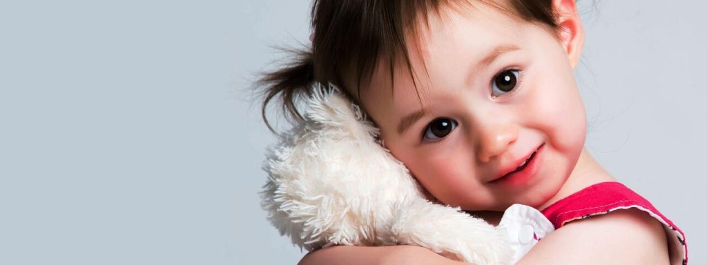 Girl cuddling teddy bear in ad for children's eye care