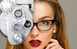 close up on blonde woman with red lips looking through eye exam technology while wearing eyeglasses