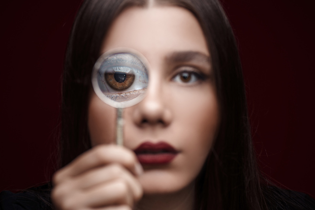 Woman experiencing dry eye, holding magnifying glass