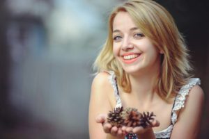 Woman Smiling Holding Pine Cone 1280×853