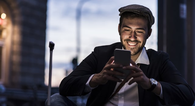 man smiling browsing his smartphone 640×350