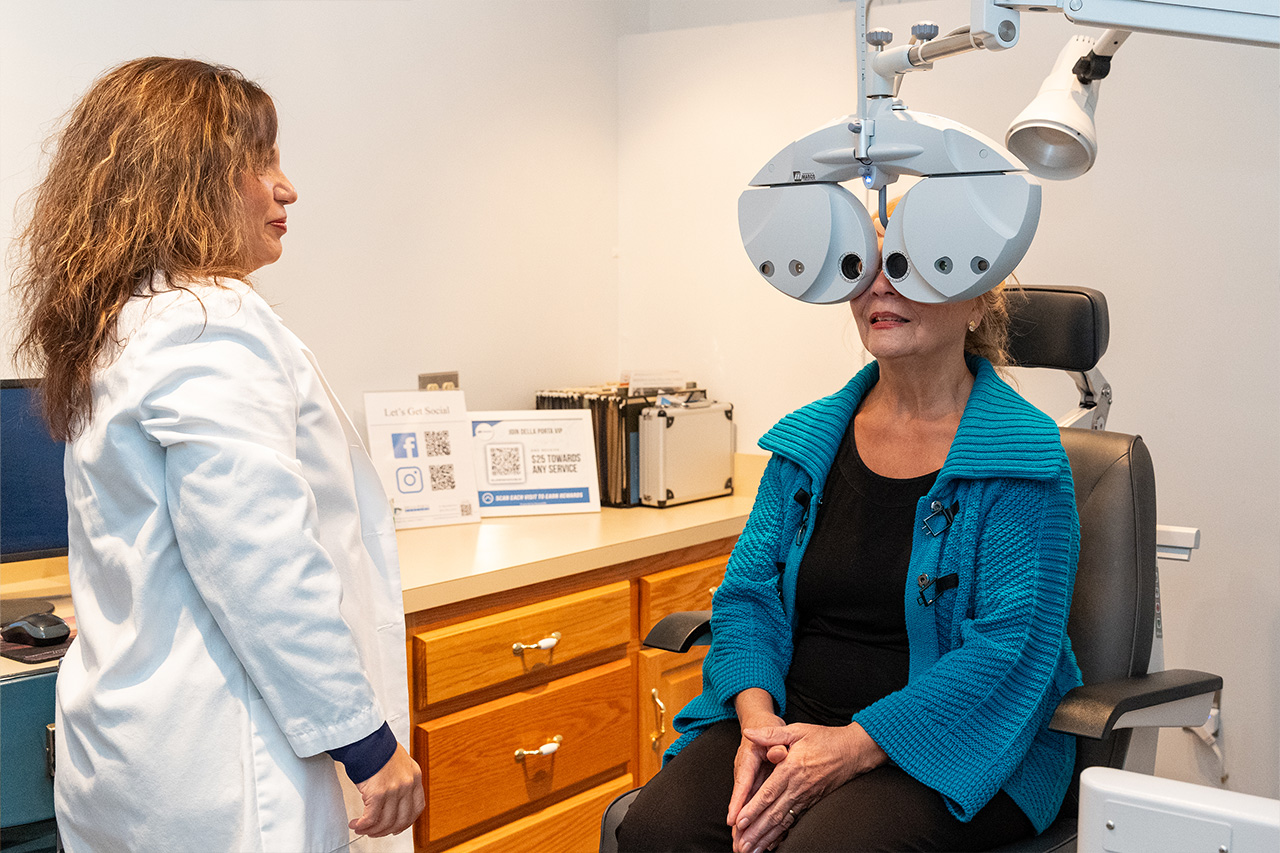 Eye doctor examining female patients eyes with phoropter