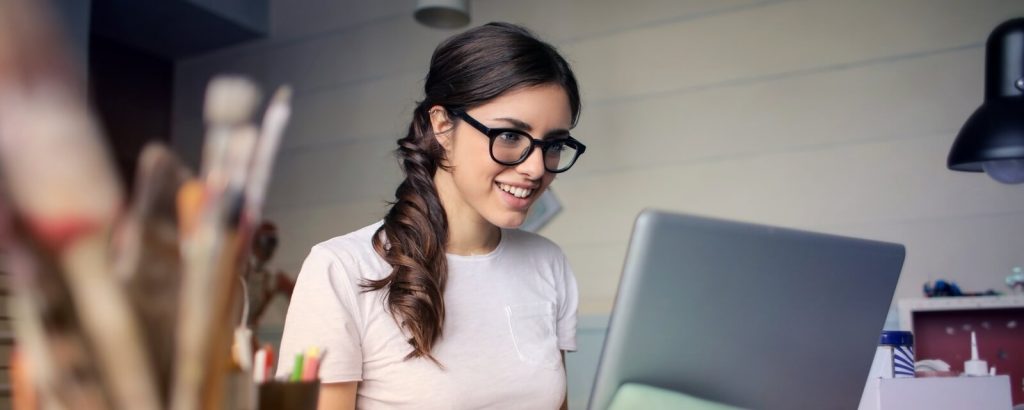 girl smiling looking at a laptop screen