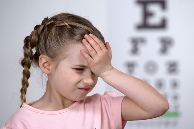 kid with headache and eye exam in the background