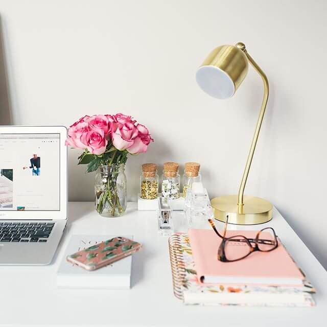 Eyeglasses, roses and a laptop on a desk