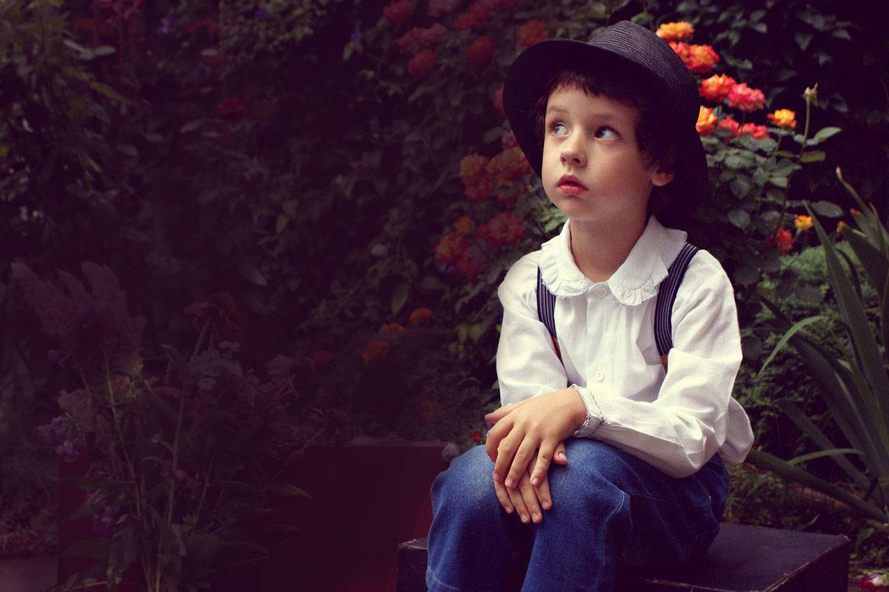 Boy wearing Hat Sitting in Garden 