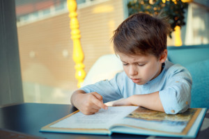 boy at a table having trouble reading