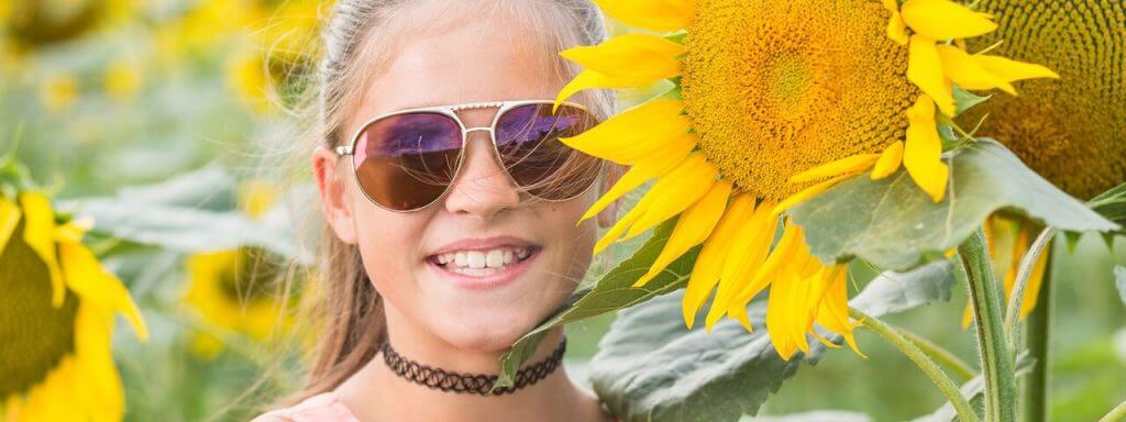 Girl wearing sunglasses in a field of sunflowers