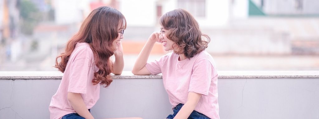 2 girls in pink shirts laughing by the window