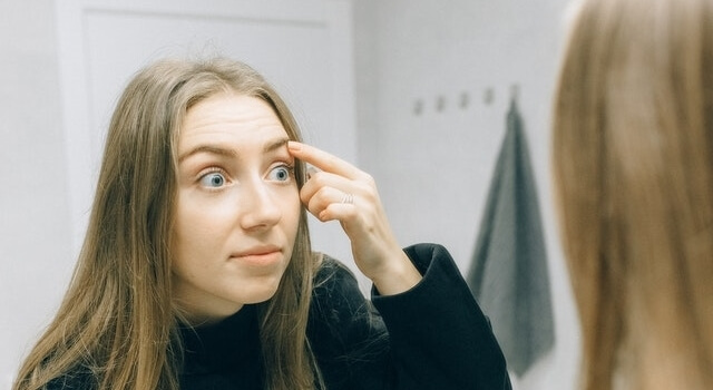 girl putting on a contact lens 640×350