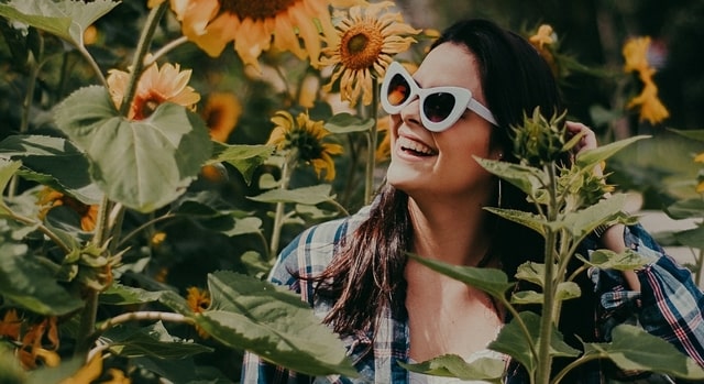 happy woman wearing sunglasses in a field of sunflowers 640x350.jpg