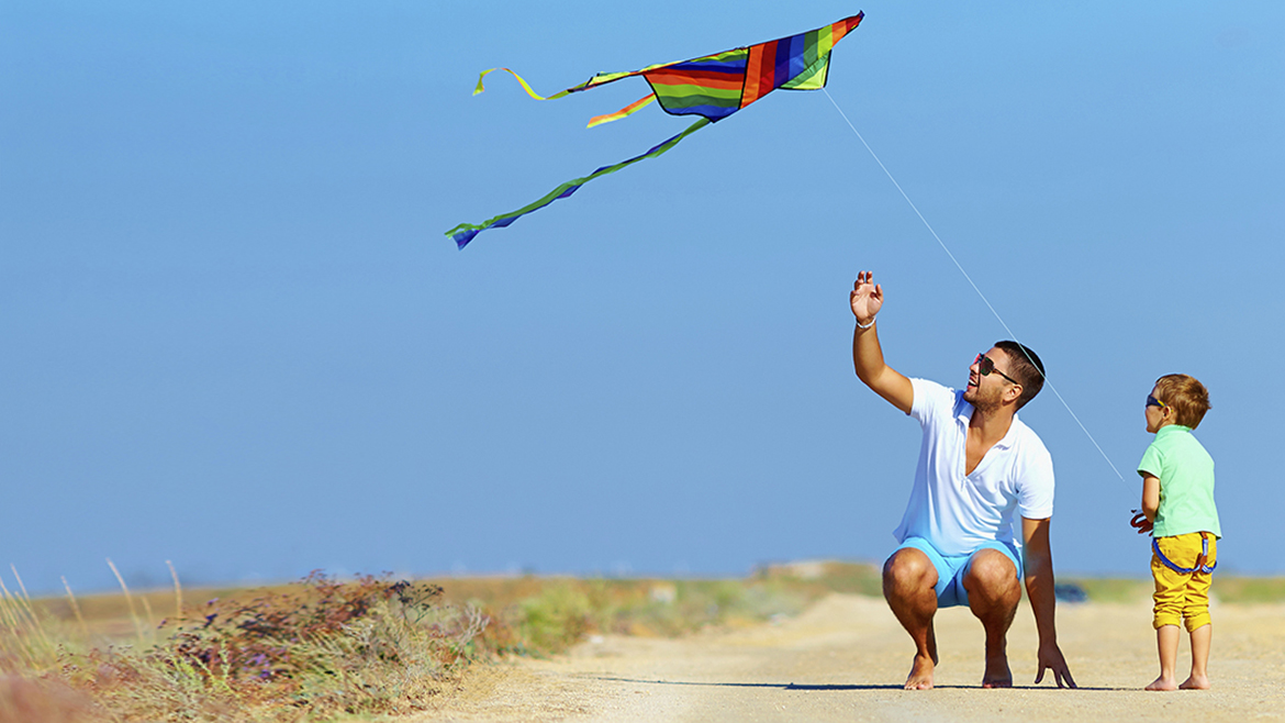 father and son having fun, playing with kite together