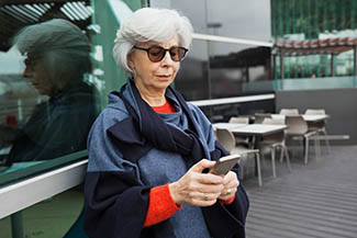 Serious Focused Lady In Sunglasses Using Mobile Phone. Grey Hair