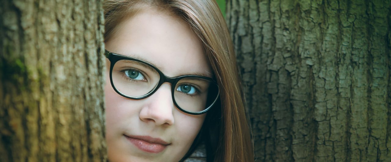 eye exam, Child with glasses peering between tree in Athens, GA
