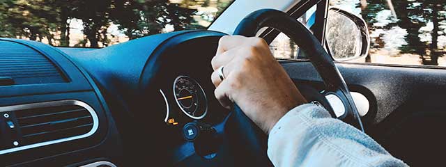 Person with Retinitis Pigmentosa holding steering wheel of car
