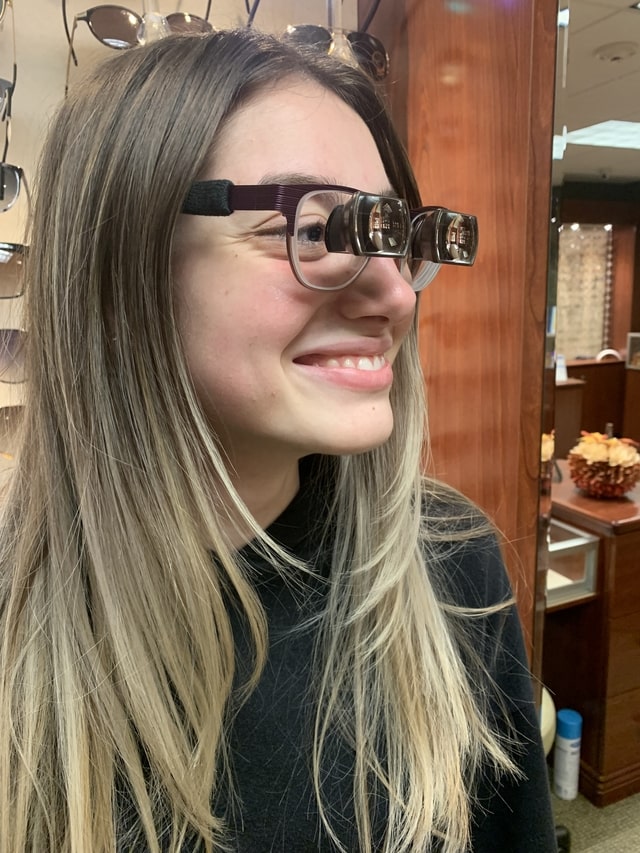 happy teenage girl wearing low vision glasses