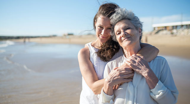 Elderly woman hugging daughter on the beach