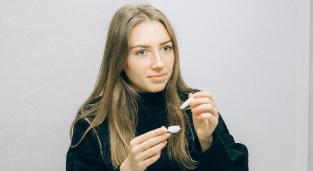 young woman putting in contact lens