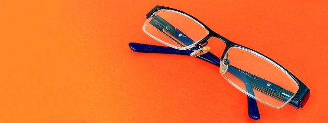 Eye doctor, pair of eyeglasses on orange surface in Toronto, ON
