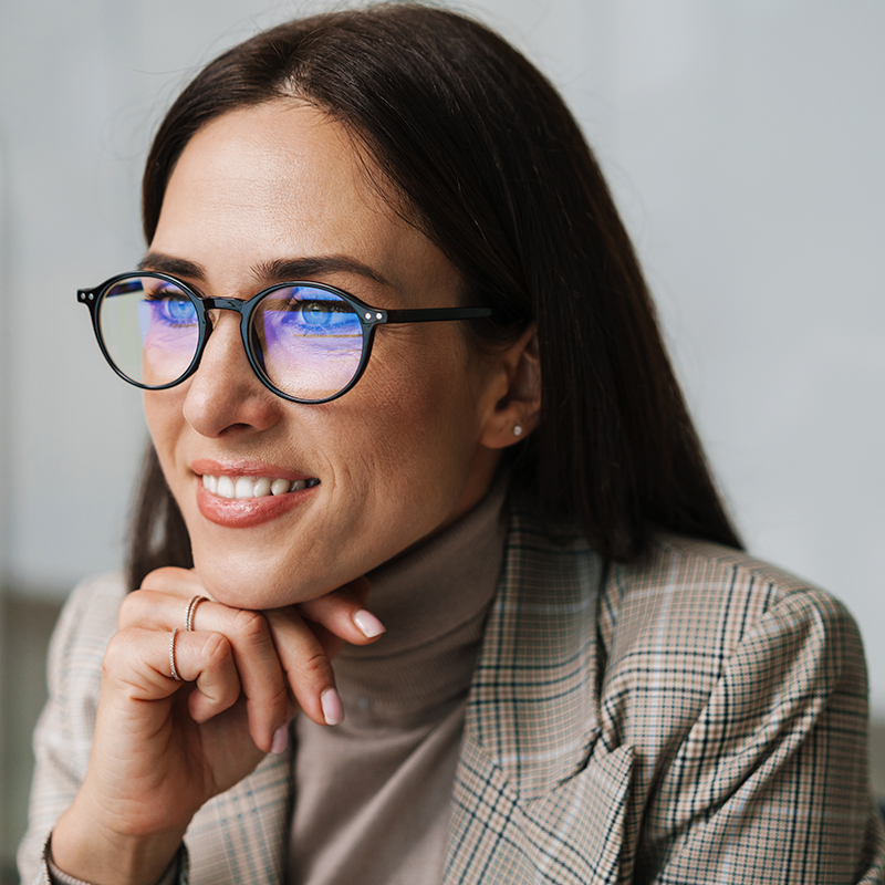 Smiling charming woman in eyeglasses working with computer in office