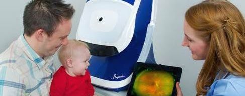Eye doctor showing optos scan to father and baby
