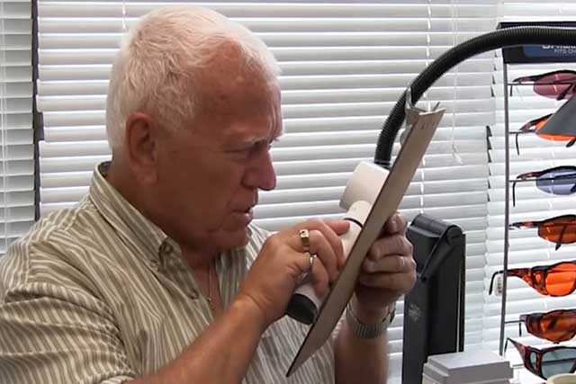 Man Using Low Vision Aid to Read Chart