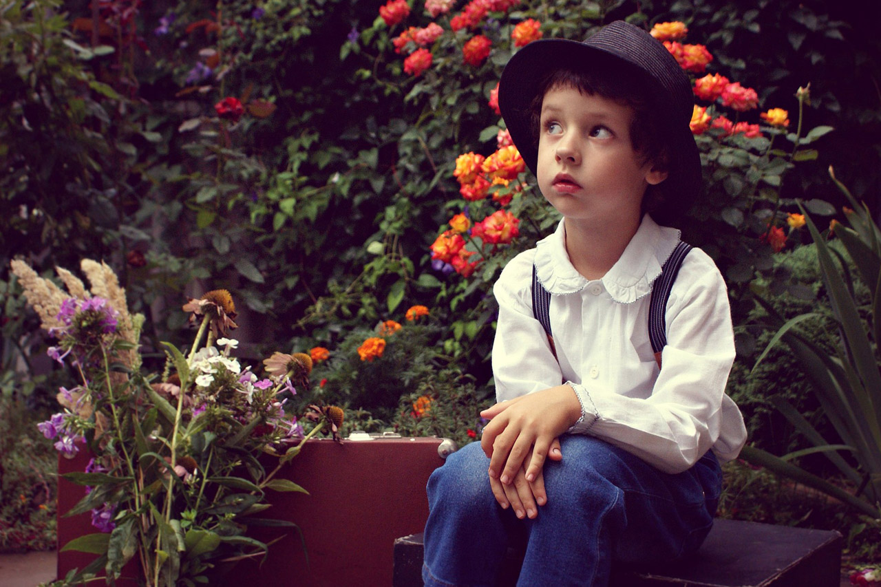 Boy wearing Hat Sitting in Garden 