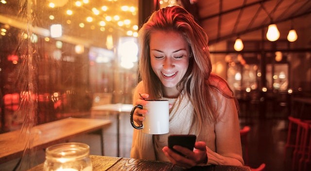 woman drinking coffee browsing her phone