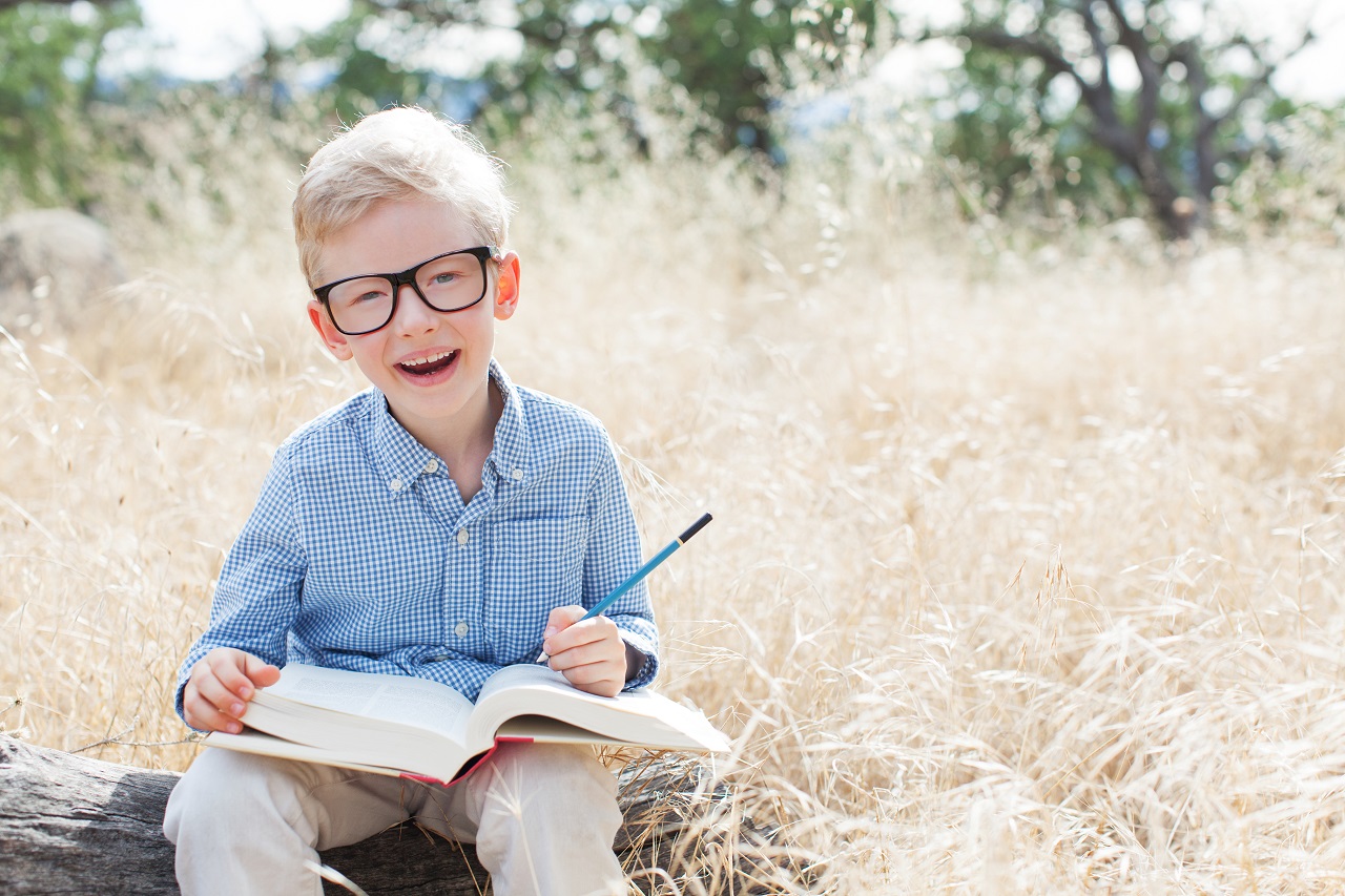 cheerful schoolboy in glasses studying, back to school concept
