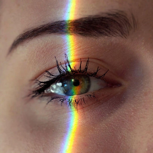 close up of an eye with slice of rainbow light over it.jpg
