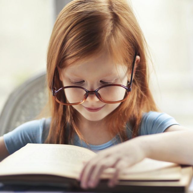 red headed girl with. glasses reading