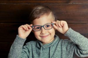 Child hipster smiling on wooden background. A kid likes the glasses.