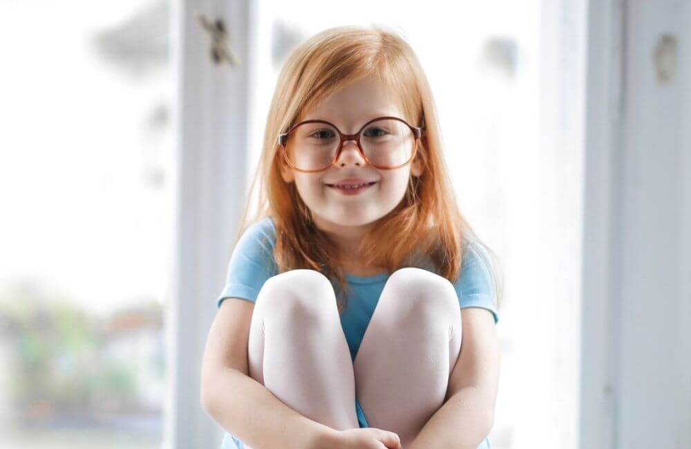 child-girl-redhead-smiling-glasses-blue-ballet-dress