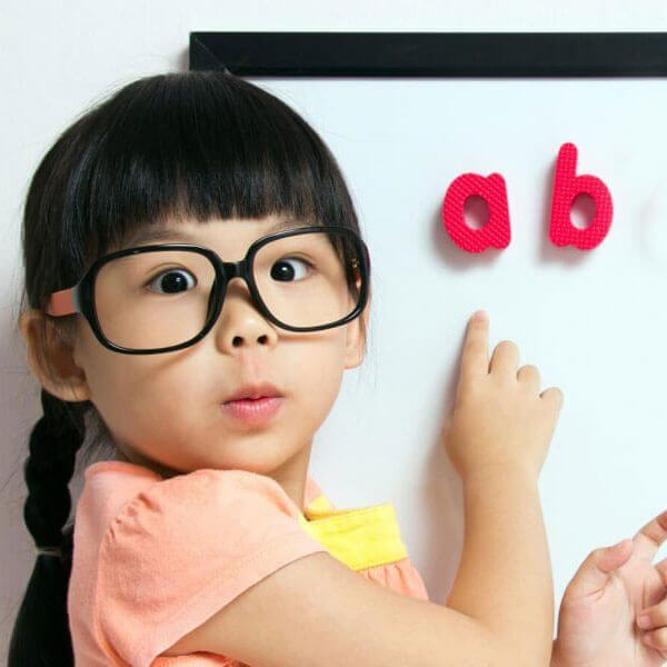 Girls wearing glasses pointing to letters on a whiteboard