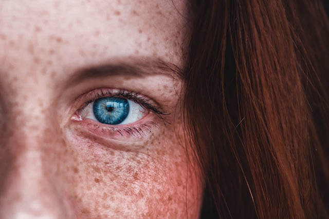 closeup on a blue eye of a red head woman