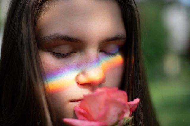 Girl closing eyes, smelling flower